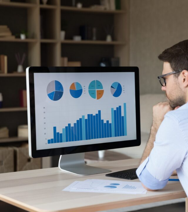 Man analyzing charts and graphs on desktop monitor